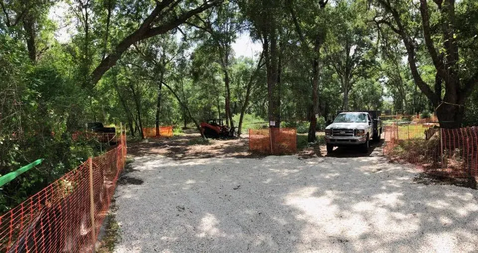 Access drive with safety fencing, truck and skid steer on a clearing job near DeLand, FL